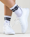 white sneakers highlighting white crews socks with charcoal stripes and pickleballs on the ankle. 
